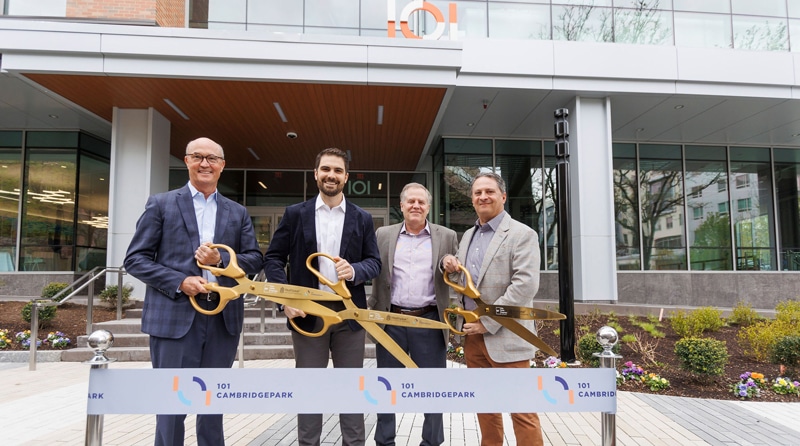 Men standing outside a new life science complex with scissors