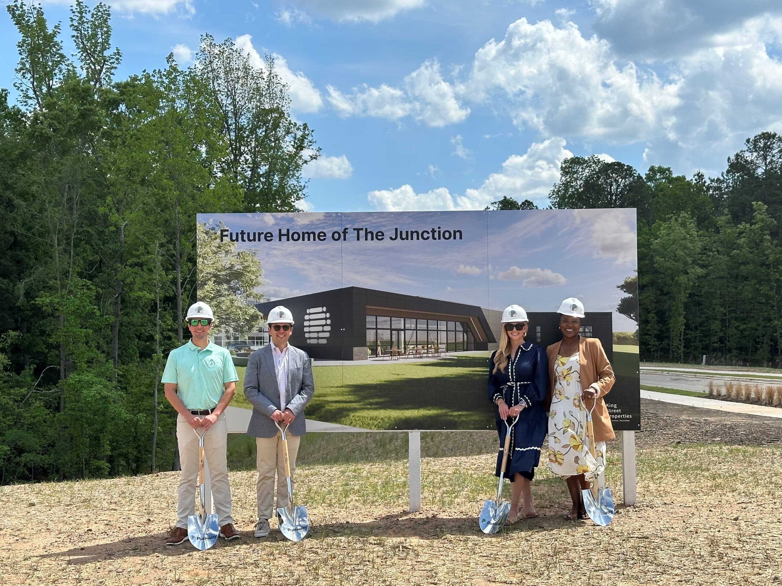 4 people standing in front of sign for The Junction at Pathway Triangle